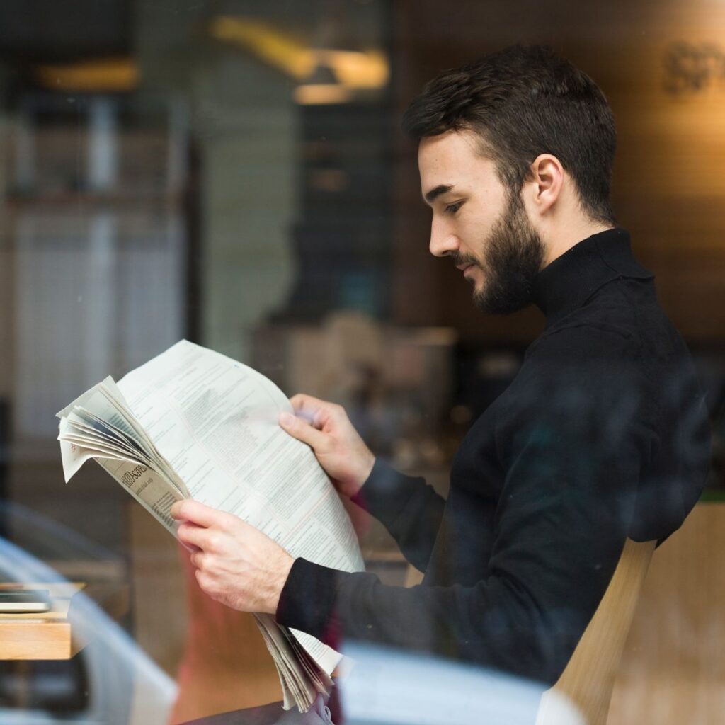 Homme lisant le journal à la fenêtre d’un café
