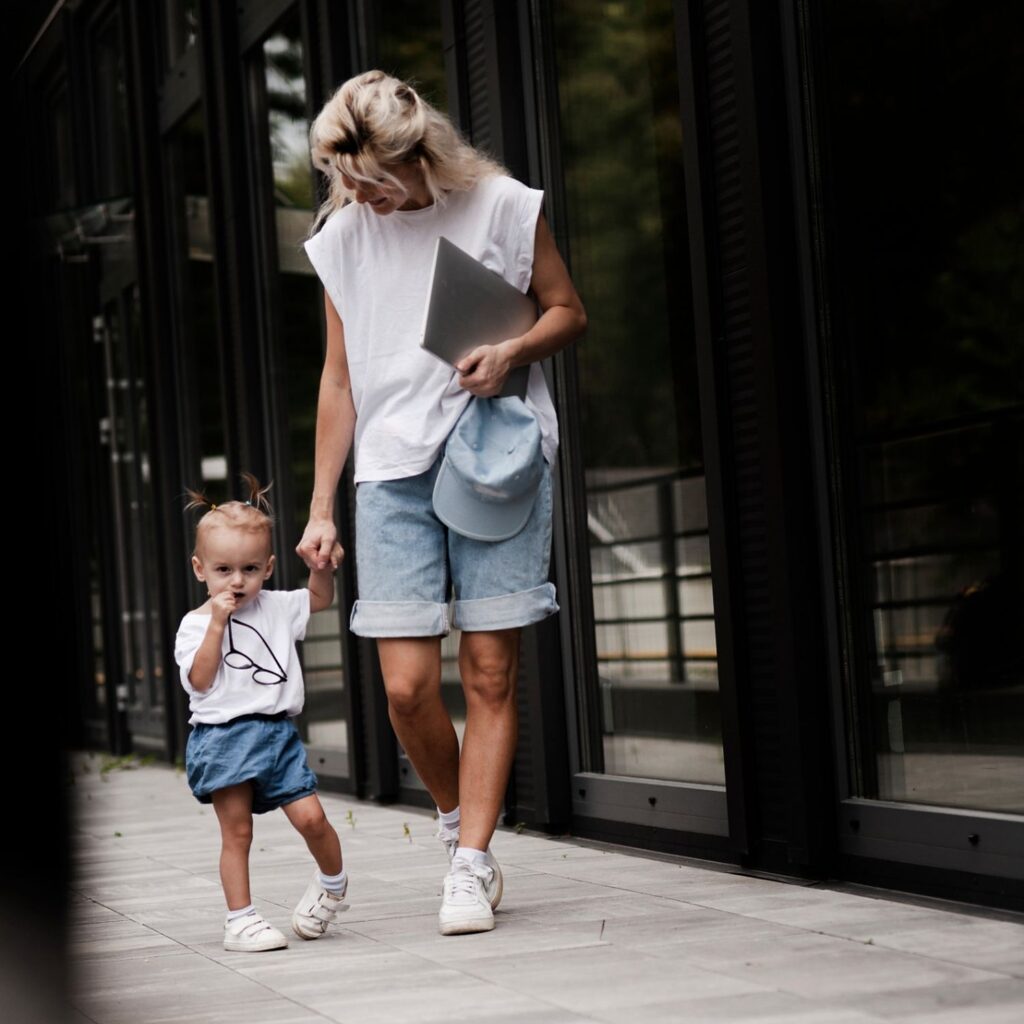 Adulte et jeune enfant marchant main dans la main le long d’un immeuble vitré